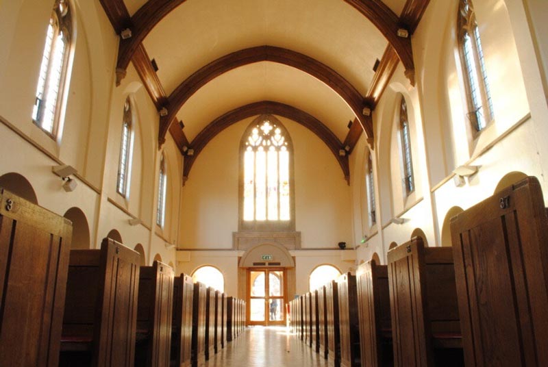 A view towards the back of a light and airy church with sunlight glowing through the windows.