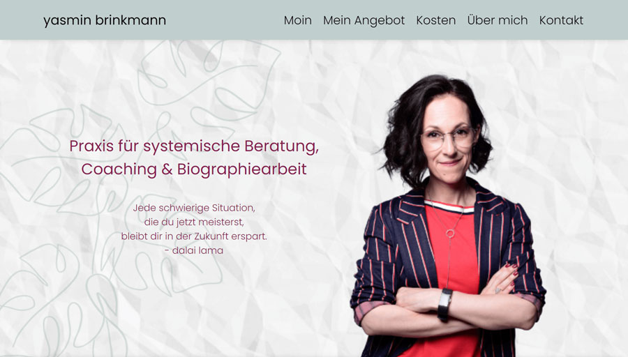 Yasmin Brinkmann's website - the headline is Praxis für systemische Beratung, Coaching & Biographiearbeit and there is a picture of her with her arms folded wearing a red top and a fetchingly striped blazer.